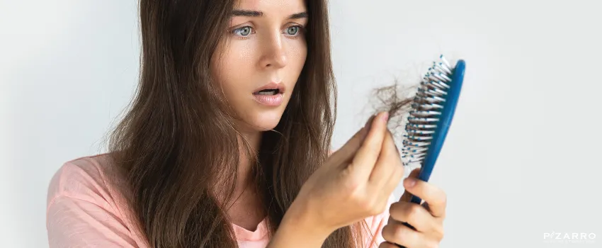 Woman staring at fallen hair from a hair brush